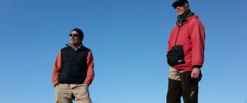 a couple of men standing on top of a hill