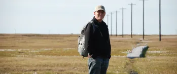 a man standing in a field with a backpack