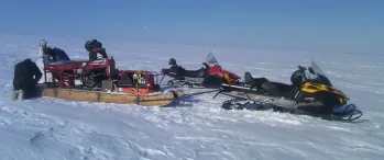 a group of people standing around snowmobiles in the snow