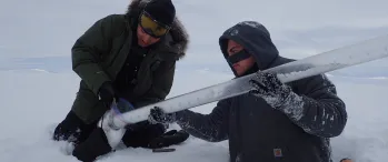 two people in the snow retrieving an ice core